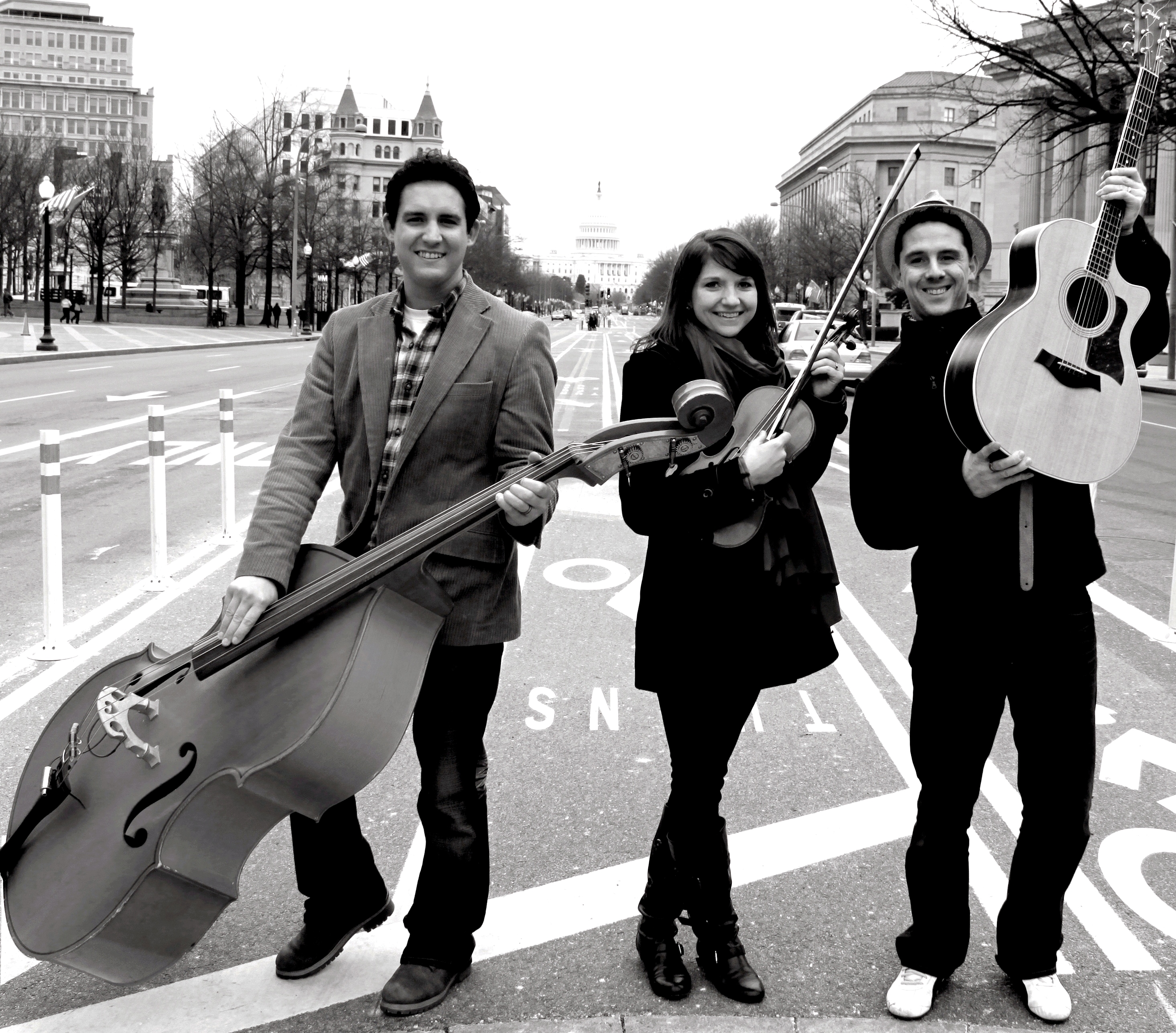 The 19th Street band trio with bass, violin, and guitar standing in DC street