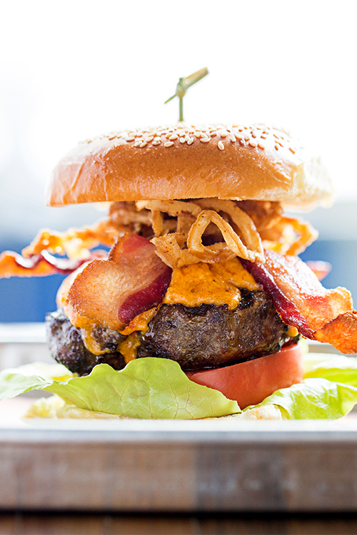 Burger with bacon and onion rings at waterfront restaurant