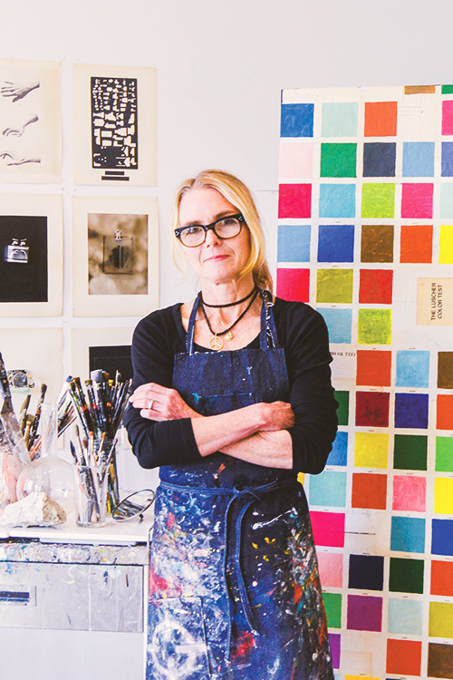 Artist Julie Wolfe in a paint covered smock posing in her studio