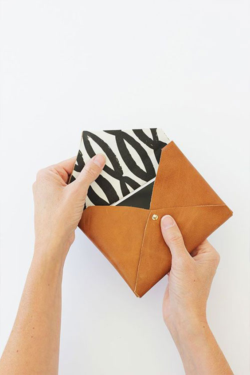Opening a handcrafted leather pouch from a DIY class in DC