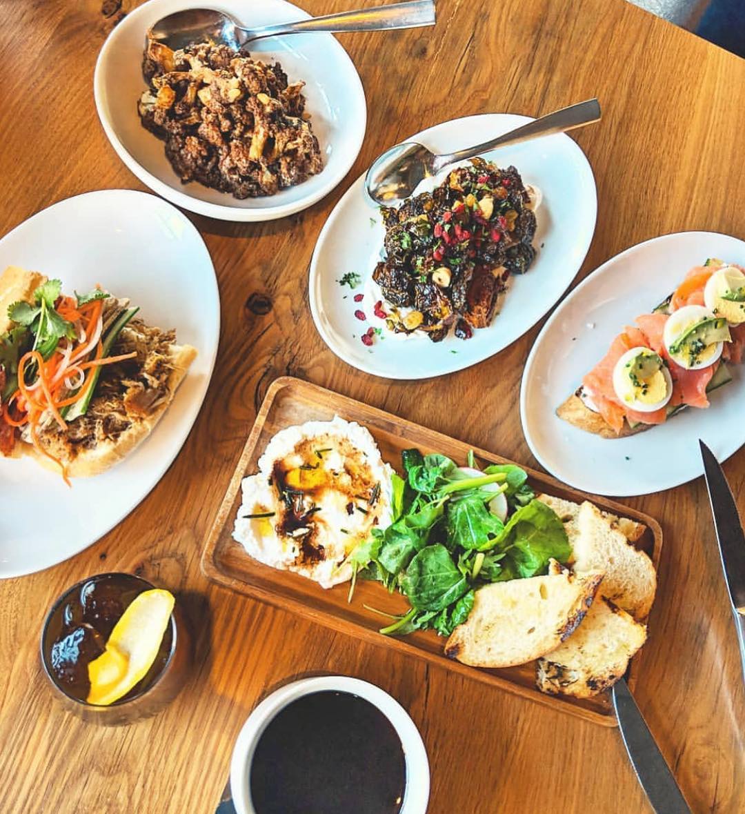 Plates full of dips, spreads, and vegetables on a dinner table