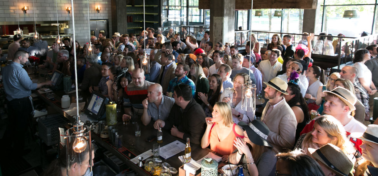 Crowded sports bar patrons watch tv during a summer event